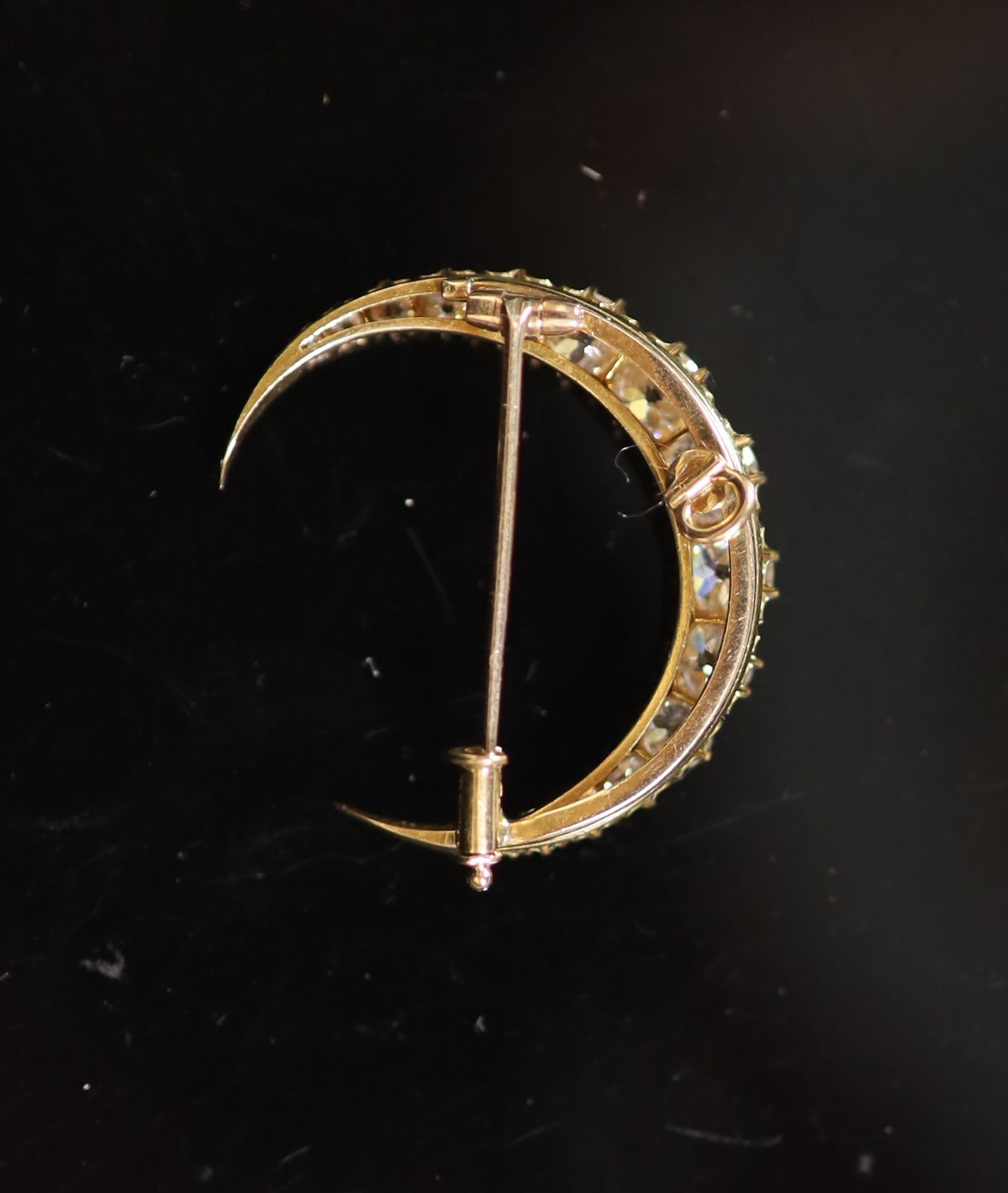 A gold and graduated fifteen stone old round cut diamond set crescent pendant brooch